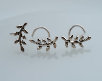 May include: Three silver nose rings with a leaf design. The rings are curved and have a small bead at the end.