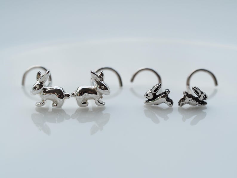 K&ouml;nnte beinhalten: Ein Paar silberne Hasenohr-Ohrstecker und ein Paar silberne Hasenohr-Nasenringe.