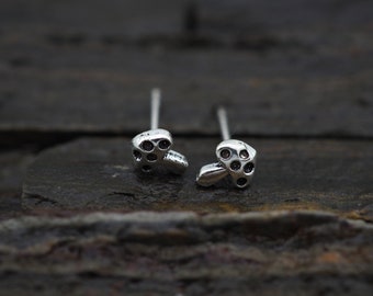 May include: A pair of silver mushroom stud earrings with black dots on the mushroom caps.
