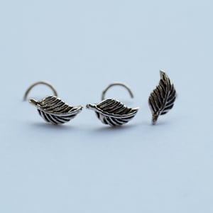 May include: Three silver nose rings with a leaf design. The leaves are detailed and have a textured finish.
