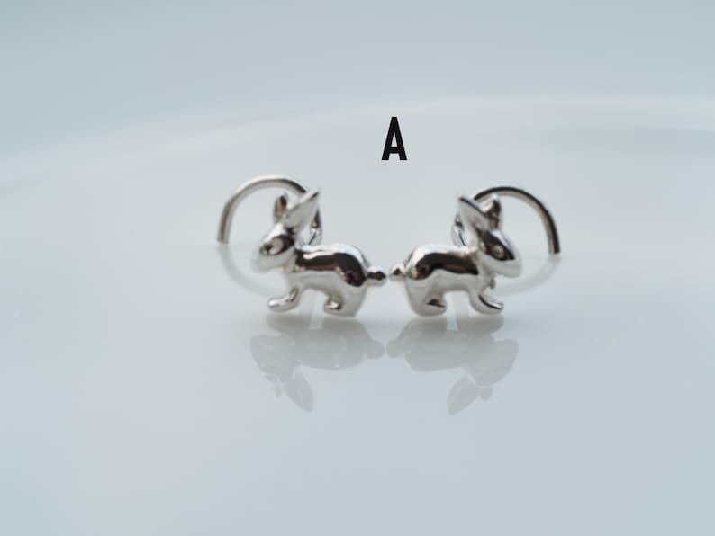 K&ouml;nnte beinhalten: Ein Paar silberne Ohrstecker in Form von Hasen. Die Hasen sind in die gleiche Richtung gewandt und in einer Gehpose.