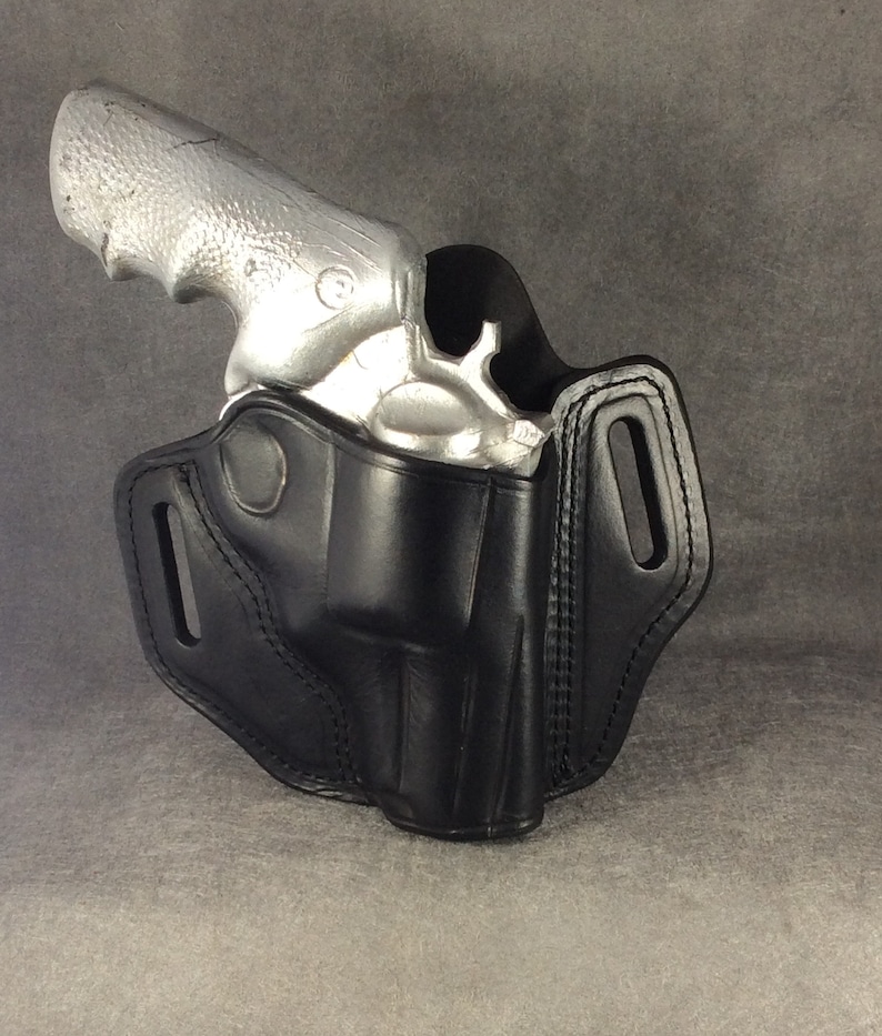 May include: A black leather holster for a silver revolver. The holster has a belt loop and a snap closure.