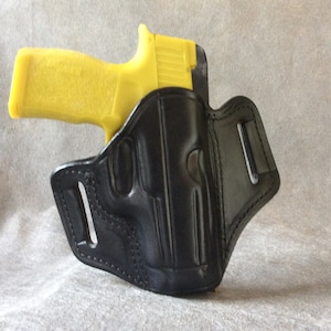 以下が含まれることがあります： 銃器用の黒い革製ホルスター。ホルスターにはベルトループと銃を固定するためのストラップが付いています。銃は含まれていません。
