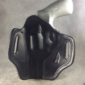 May include: Black leather holster with a stitched design. The holster is designed to hold a small silver handgun.