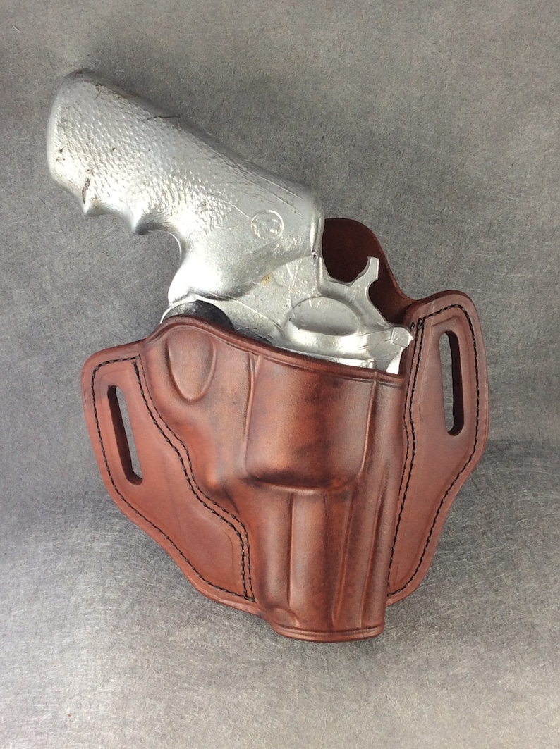 May include: A brown leather holster for a silver revolver. The holster has a belt loop and a snap closure.