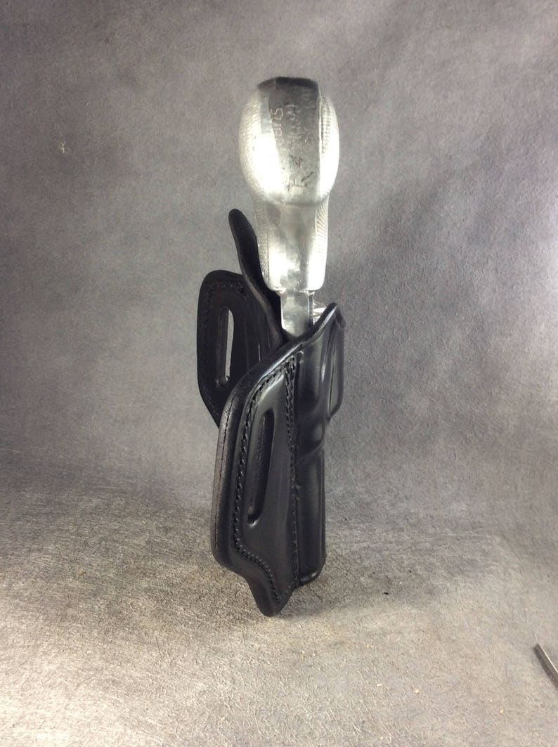 May include: A black leather holster with a silver metal gun inside.