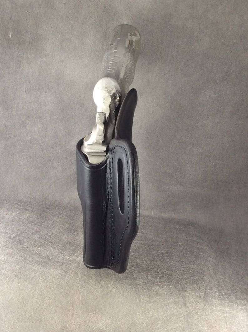 May include: A black leather holster for a handgun. The holster has a stitched design and a belt loop.