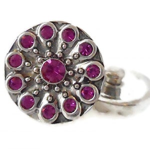 May include: A silver nose ring with a pink rhinestone flower design.