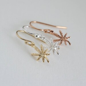 May include: Three pairs of dangle earrings with a marijuana leaf design. The earrings are available in gold, silver, and rose gold.