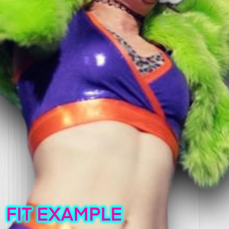 May include: A purple and orange crop top with a shiny, wet look. The top has a wrap-style design and a contrasting orange band around the waist. The top is worn over a black and white patterned top.