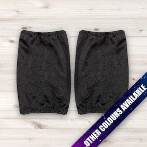 May include: Two black arm warmers made of a stretchy fabric. The arm warmers are lying flat on a light wood surface. Other colours are available.