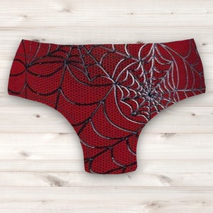 Puede incluir: Ropa interior roja con un patrón de telaraña negra y plateada.