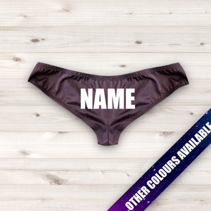 May include: Brown underwear with the word "NAME" in white block letters across the front. The underwear is made of a shiny material. A banner in the lower right corner reads "OTHER COLORS AVAILABLE".