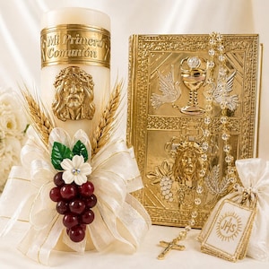 May include: A religious set featuring a candle with "Mi Primera Comunión" text, a gold-colored book, and a rosary. The candle has a gold Jesus face, wheat stalks, and a ribbon with grapes. The book and rosary are gold-colored.