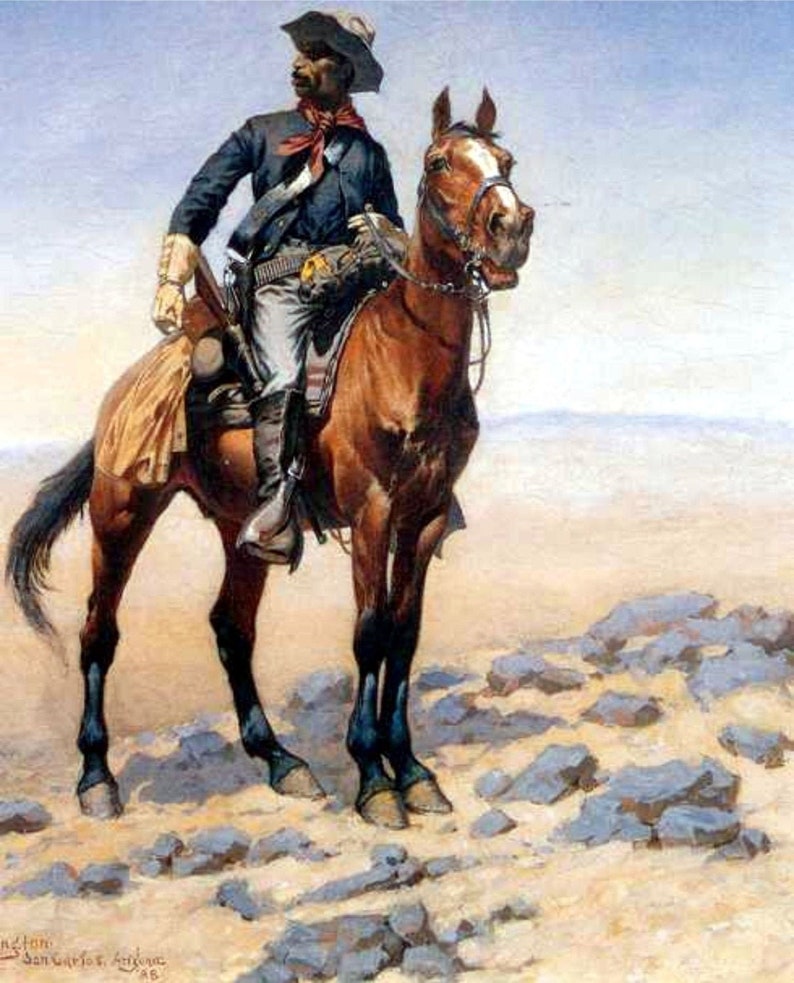 Puede incluir: Un hombre negro con un uniforme azul y un pa&ntilde;uelo rojo monta un caballo marr&oacute;n con una estrella blanca en la cara. El hombre sostiene un rifle y el caballo est&aacute; de pie sobre una superficie rocosa y arenosa.