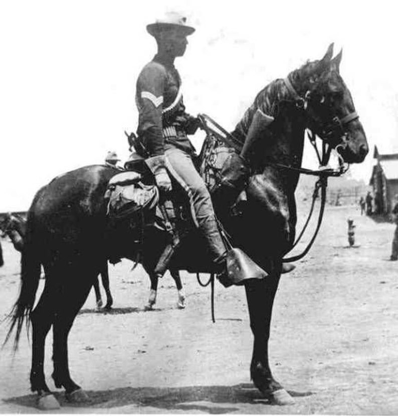 Puede incluir: Una fotograf&iacute;a en blanco y negro de un hombre con uniforme montando a caballo. El hombre lleva un sombrero y sostiene las riendas. El caballo lleva una brida y tiene una silla de montar.