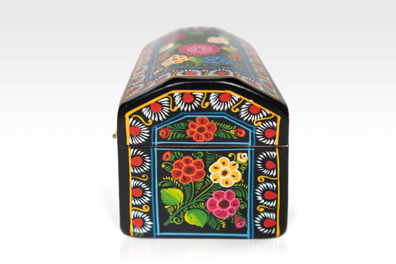 May include: A black, arched-top wooden box with a hinged lid. The box is adorned with a vibrant floral design in red, orange, yellow, and pink, set against a black background. The edges are decorated with white and yellow accents.