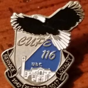 May include: A silver and blue enamel pin with a black and white eagle design. The pin features the text "CUPE 116" and "SERVICE 1942 75 YEARS 2017 LOYALTY" around the eagle.