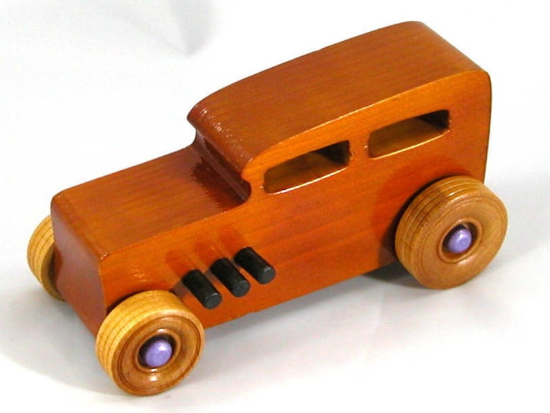 This is a handmade wooden toy car modeled after a Hot Rod 1932 Ford Sedan. It is made from wood, finished with multiple coats of amber shellac, and trimmed with black and metallic purple acrylic paint.