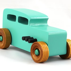 Handmade wooden toy car, 1932 Hot Rod Sedan, painted turquoise with metallic green and black trim. The wheels are finished with nonmarring amber shellac. Handcrafted from natural wood in Tallahassee, Florida, USA. Approximate size: 6 inches long, 3 inches high, 2.5 inches wide. Odin's Toy Factory custom wooden toy.