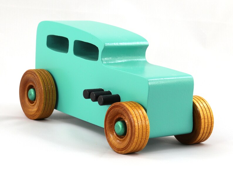 Handmade wooden toy car, 1932 Hot Rod Sedan, painted turquoise with metallic green and black trim. The wheels are finished with nonmarring amber shellac. Handcrafted from natural wood in Tallahassee, Florida, USA. Approximate size: 6 inches long, 3 inches high, 2.5 inches wide. Odin's Toy Factory custom wooden toy.