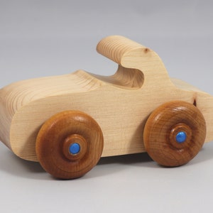 Handmade wooden toy car. The body is finished with clear shellac, and the wheels are finished with amber shellac. The hubs are painted with metallic sapphire blue trim.