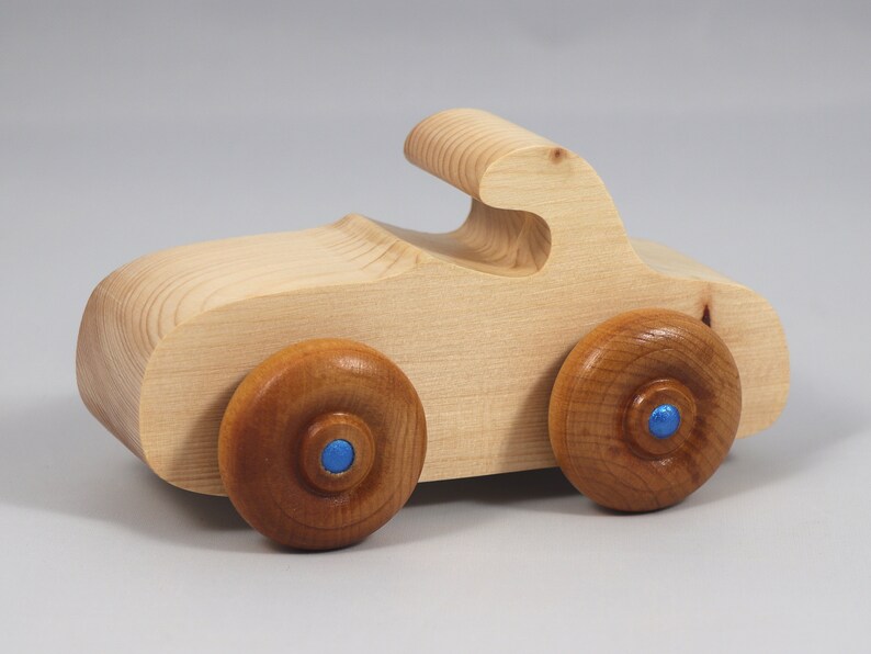 Handmade wooden toy car. The body is finished with clear shellac, and the wheels are finished with amber shellac. The hubs are painted with metallic sapphire blue trim.