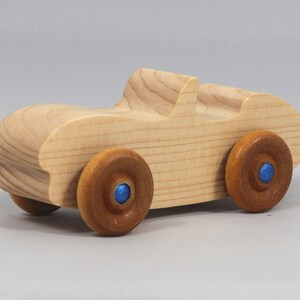 Handmade wooden toy car convertible sports coupe with a nontoxic satin polyethylene finish, amber shellac wheels, and metallic sapphire blue trim.