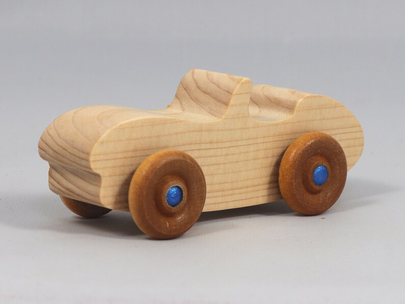 Handmade wooden toy car convertible sports coupe with a nontoxic satin polyethylene finish, amber shellac wheels, and metallic sapphire blue trim.