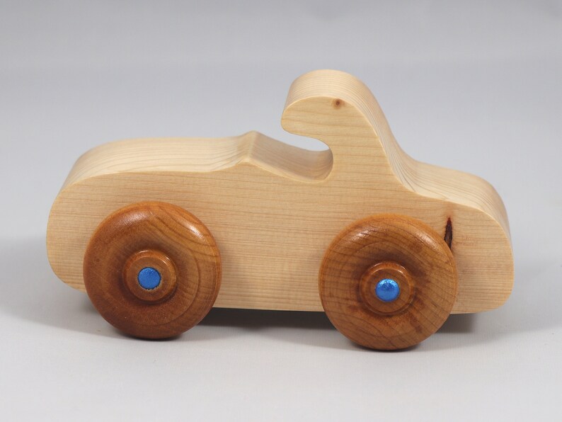 Handmade wooden toy car. The body is finished with clear shellac, and the wheels are finished with amber shellac. The hubs are painted with metallic sapphire blue trim.