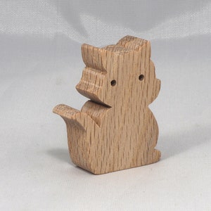 May include: A wooden squirrel figurine with a light brown finish. The squirrel is standing on its hind legs with its tail curled behind it.