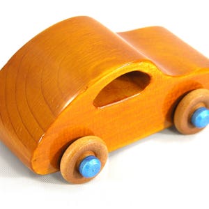 A handmade wooden toy car modeled after the iconic 1957 bug, finished with amber shellac and metallic sapphire blue trim. It's part of my Play Pal Collection.