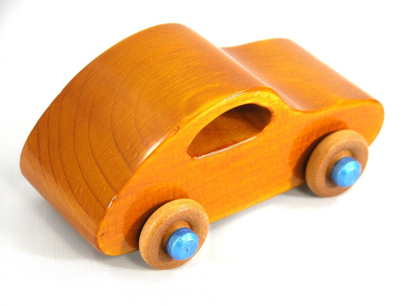A handmade wooden toy car modeled after the iconic 1957 bug, finished with amber shellac and metallic sapphire blue trim. It's part of my Play Pal Collection.