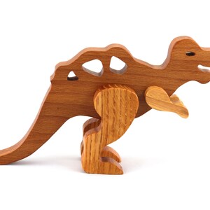 May include: A wooden toy dinosaur with a brown finish. The dinosaur has a long tail, a small head, and a row of spikes down its back.