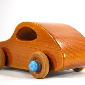 A handmade wooden toy car modeled after the iconic 1957 bug, finished with amber shellac and metallic sapphire blue trim. It's part of my Play Pal Collection.