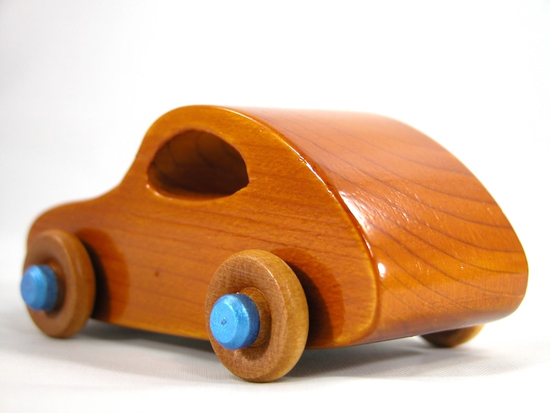 A handmade wooden toy car modeled after the iconic 1957 bug, finished with amber shellac and metallic sapphire blue trim. It's part of my Play Pal Collection.