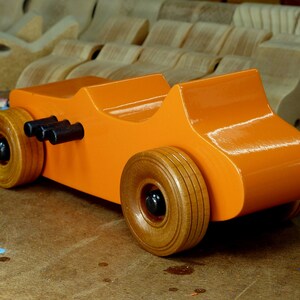 Handmade wooden toy car modeled after a 1927 T-Bucket hot rod. Finished with orange and black acrylic paint and amber shellac.