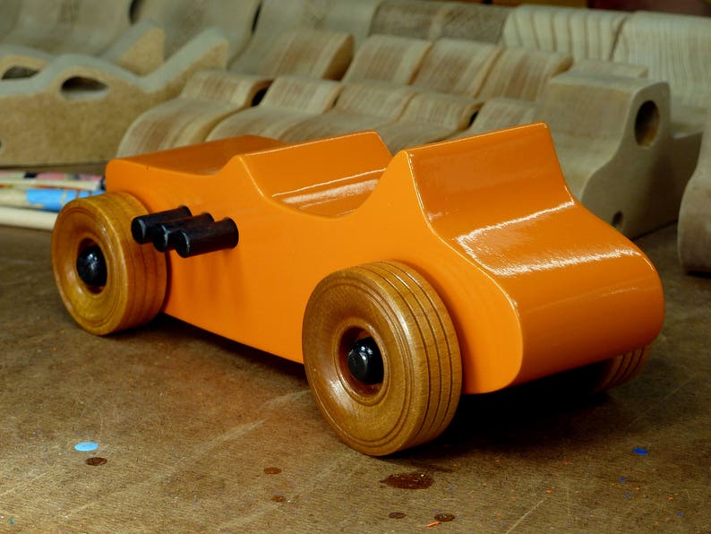 Handmade wooden toy car modeled after a 1927 T-Bucket hot rod. Finished with orange and black acrylic paint and amber shellac.