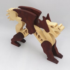 Handmade wooden dragon figurine. crafted from contrasting hardwoods with a light natural wood body and head paired with rich dark reddish-brown wings, legs, and horns.