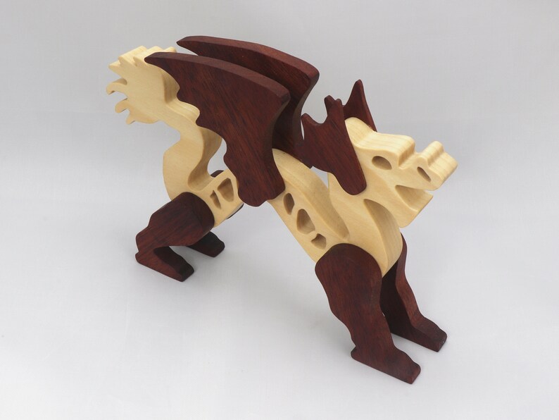 Handmade wooden dragon figurine. crafted from contrasting hardwoods with a light natural wood body and head paired with rich dark reddish-brown wings, legs, and horns.
