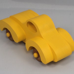 Handmade wooden toy car vintage style of a fat fendered coupe painted bright yellow with nonmarring amber shellac finished wheels. It is an excellent push toy for a younger child.