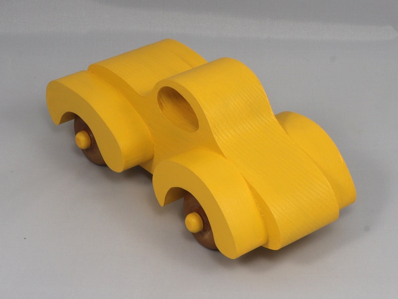 Handmade wooden toy car vintage style of a fat fendered coupe painted bright yellow with nonmarring amber shellac finished wheels. It is an excellent push toy for a younger child.