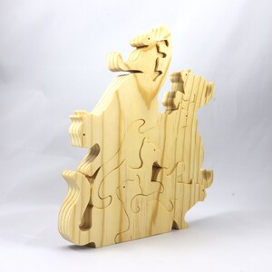 Handmade wooden puzzle featuring several cat-shaped pieces stacked on top of each other in various playful poses, forming a balanced tower. The cats are crafted with smooth edges and natural wood tones, highlighting their unique shapes and expressions.