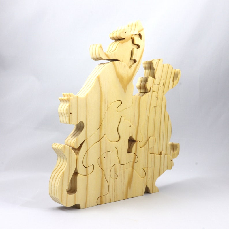 Handmade wooden puzzle featuring several cat-shaped pieces stacked on top of each other in various playful poses, forming a balanced tower. The cats are crafted with smooth edges and natural wood tones, highlighting their unique shapes and expressions.