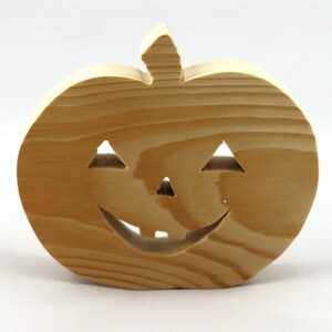 Handmade unpainted wooden Jack-o-Lantern cutout with carved triangular eyes, nose, smiling mouth, and stem, shown freestanding on a white background. Ready to paint for Halloween decoration.