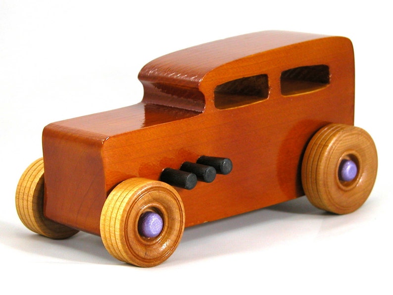 This is a handmade wooden toy car modeled after a Hot Rod 1932 Ford Sedan. It is made from wood, finished with multiple coats of amber shellac, and trimmed with black and metallic purple acrylic paint.