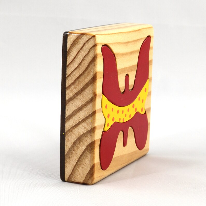 A wooden three-piece butterfly tray puzzle, handmade and finished. The butterfly is painted bright red and yellow with orange spots. The wooden tray is finished with clear shellac. It is one of four puzzles in my Puzzle Pals Collection.