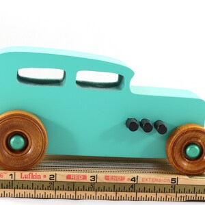 Handmade wooden toy car, 1932 Hot Rod Sedan, painted turquoise with metallic green and black trim. The wheels are finished with nonmarring amber shellac. Handcrafted from natural wood in Tallahassee, Florida, USA. Approximate size: 6 inches long, 3 inches high, 2.5 inches wide. Odin's Toy Factory custom wooden toy.