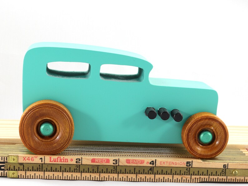 Handmade wooden toy car, 1932 Hot Rod Sedan, painted turquoise with metallic green and black trim. The wheels are finished with nonmarring amber shellac. Handcrafted from natural wood in Tallahassee, Florida, USA. Approximate size: 6 inches long, 3 inches high, 2.5 inches wide. Odin's Toy Factory custom wooden toy.