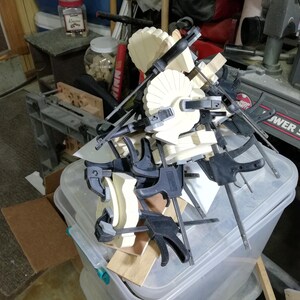 Wooden turkey bodies and wing pieces held together with clamps while the glue dries in the workshop.